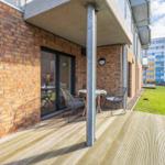 Terrasse mit Tisch und Stühlen neben einem Haus mit Backsteinfassade.