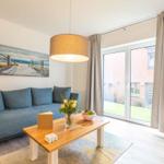 Wohnzimmer mit Sofa, Tisch und Fenster zur Terrasse.