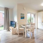 Wohnküche mit Esstisch, TV und Fenster zur Terrasse.