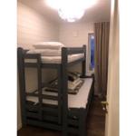 Zimmer mit Doppelstockbett, Fenster und Holzboden.