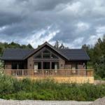 Holzhaus mit Balkon und großem Fenster unter bewölktem Himmel