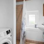 Badezimmer mit Waschmaschine, Dusche und Waschbecken