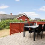 Terrasse mit Tisch und Stühlen, roter Holzzaun, Blick auf rote Häuser und Grünflächen.