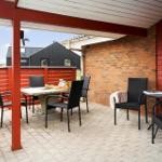 Terrasse mit Tisch, Stühlen und Sitzgelegenheiten unter Pavillon.