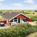 Rotes Ferienhaus mit Terrasse und Garten. Blick auf grüne Landschaft.