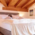 Schlafzimmer mit Bett, Holzdecke und Wanddekoration.