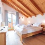 Schlafzimmer mit Holzboden, Dachschräge und Balkonzugang.