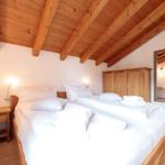 Schlafzimmer mit Doppelbett, Holzboden und Holzdecke mit Balken.