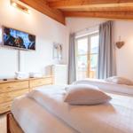 Schlafzimmer mit Doppelbett, Fernseher und Blick auf die Berge.