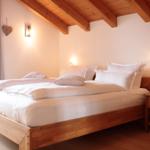 Ein Schlafzimmer mit Holzbett, Nachttisch und Deckenbalken.