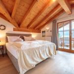 Schlafzimmer mit Holzboden, Balkon und Holzdecke mit Balken.