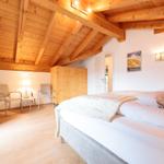 Schlafzimmer mit Holzdecke, Bett, Schrank und zwei Stühlen.