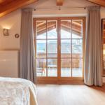 Schlafzimmer mit Blick auf Balkon und Berge. Holzdecke und Boden.