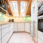 Küche mit weißen Schränken, grüner Rückwand und Dachfenstern.