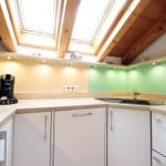 Küche mit Holzdecke, Dachfenstern und grüner Rückwand.