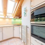 Küche mit integriertem Ofen und Dunstabzugshaube unter Dachschrägen.