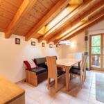 Essbereich mit Holztisch, Stühlen und Sitzbank unter Holzdecke mit Balkonanschluss.