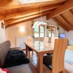 Wohn- und Essbereich mit Holzdecke, Esstisch und Sofa.