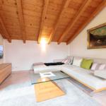 Wohnzimmer mit Sofa, Glas-Tisch und Holzdecke.