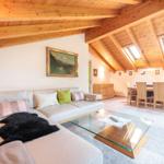 Wohn- und Essbereich mit Holzdecke, Sofa und Glas-Tisch.