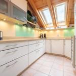 Küche mit Holzdecke, Dachfenstern und hellen Arbeitsplatten.