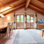 Wohn- und Essbereich mit Holzdecke, TV und Blick auf Balkon.