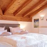 Schlafzimmer mit Holzdecke, Bett und Wandbild.