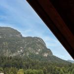 Blick auf bewaldete Berge von einem Holzdach aus.