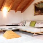 Wohnzimmer mit Sofa, Glas-Tisch und Holzdecke.