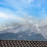 Blick auf Berge mit Wolken über einem Dach