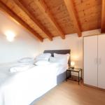 Schlafzimmer mit Holzdecke, Bett, Nachttisch und Kleiderschrank.