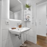 Badezimmer mit Waschbecken, Spiegel und Heizung. Durchgang zur Terrasse mit Meerblick.