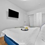 Schlafzimmer mit Bett, Fernseher und Kleiderschrank.