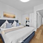 Schlafzimmer mit Bett, Kleiderschrank und Flur. Wandbild und Pflanzen.