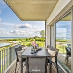 Terrasse mit Sitzgruppe und Meerblick. Tisch mit Blumen und Kerzen.