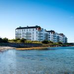 Moderne Wohnanlage am Strand mit Balkonen und klarem Himmel.