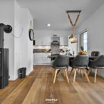 Essbereich mit Blick auf Wasser, schwarze Stühle und Kaminofen im Vordergrund.