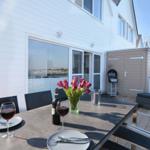 Terrasse mit Tisch, Stühlen, Grill und Blumen.