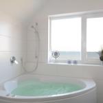Bad mit Whirlpool, Dusche und Fensterblick aufs Meer.