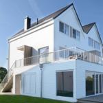 Moderne weiße Villa mit Balkon und Glasfront. Grünfläche und klare Sicht.