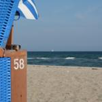 Blauer Strandkorb mit Nummer 58 und griechischer Flagge am Strand.