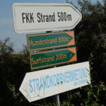 Schilder weisen auf FKK-Strand, Hundestrand und Surfstrand hin.