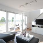 Wohnzimmer mit TV, Couch und Balkonansicht.