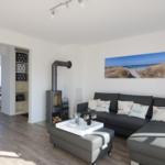 Wohnzimmer mit Sofa, Kamin und Küchenbereich im Hintergrund.