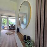 Eingangsbereich mit Spiegel, Pflanzen und Blick auf Terrasse mit Meerblick.