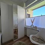 Schlafzimmer mit Kleiderschrank, Stuhl und Fenster mit Jalousie.