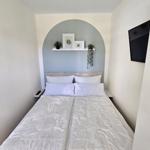 Schlafzimmer mit Doppelbett, Wandregal und Fernseher.