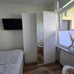 Schlafzimmer mit Bett, Kleiderschrank und TV. Fenster mit Jalousie.