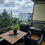 Terrasse mit Tisch, Stühlen und Blick auf Wasser und Bäume.