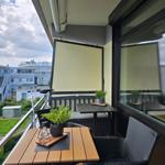 Terrasse mit Tisch, Stühlen und Pflanzen. Blick auf Wohngebiet mit Gebäuden.